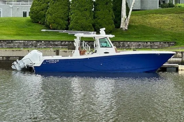 Slide: The Image of 2024 Caymas 34 CT boat with blue hull docked on calm water. - 1