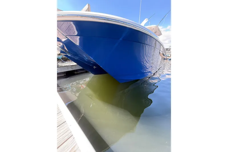 Slide: The Image of 2024 Caymas 34 CT boat with blue hull docked in calm water. - 10