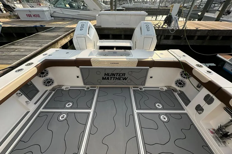 Slide: The Image of 2024 Caymas 34 CT boat deck with custom flooring and twin 400 engines at a marina. - 19