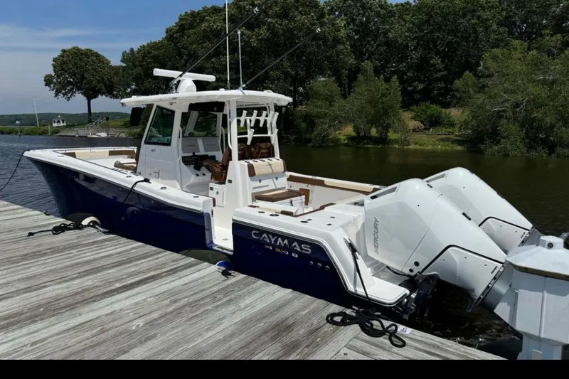 Slide: The Image of 2024 Caymas 34 CT boat docked by a scenic riverside with twin Mercury engines. - 5