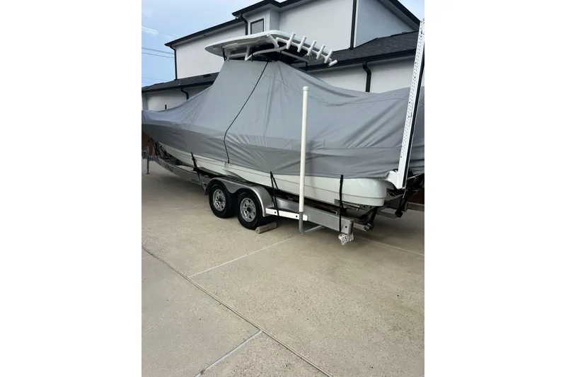 Slide: The Image of 2024 Caymas 281 HB boat covered on trailer in driveway. - 12