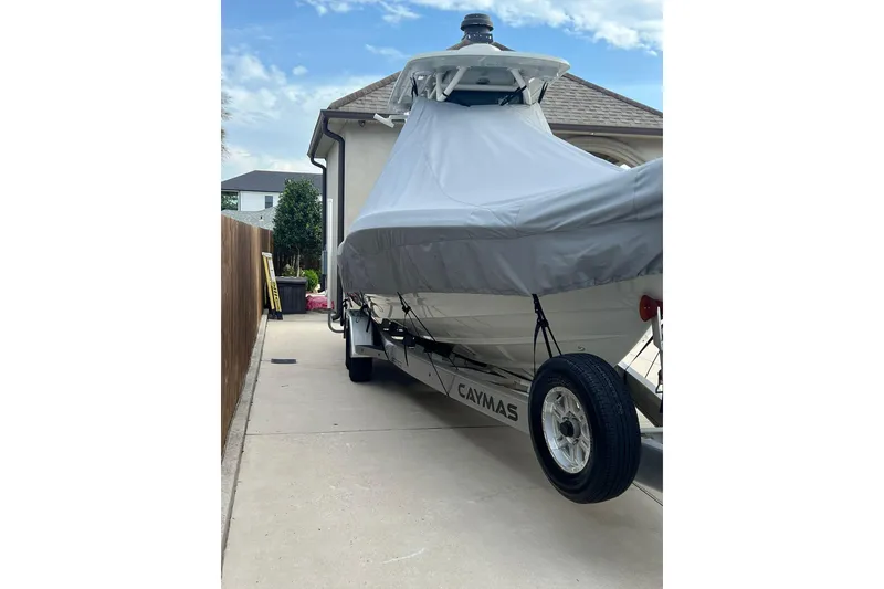 Slide: The Image of 2024 Caymas 281 HB boat covered on trailer in driveway, ready for transport. - 13