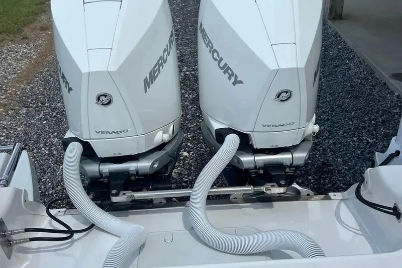 Slide: The Image of Twin Mercury Verado engines on a 2024 Caymas 281 HB boat, parked on gravel. - 6