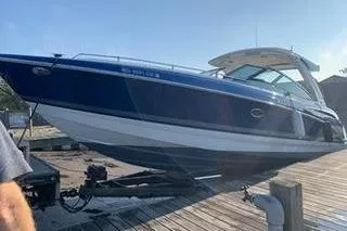 Slide: The Image of 2018 Formula 350 Crossover Bowrider on trailer at dock under clear sky. - 2