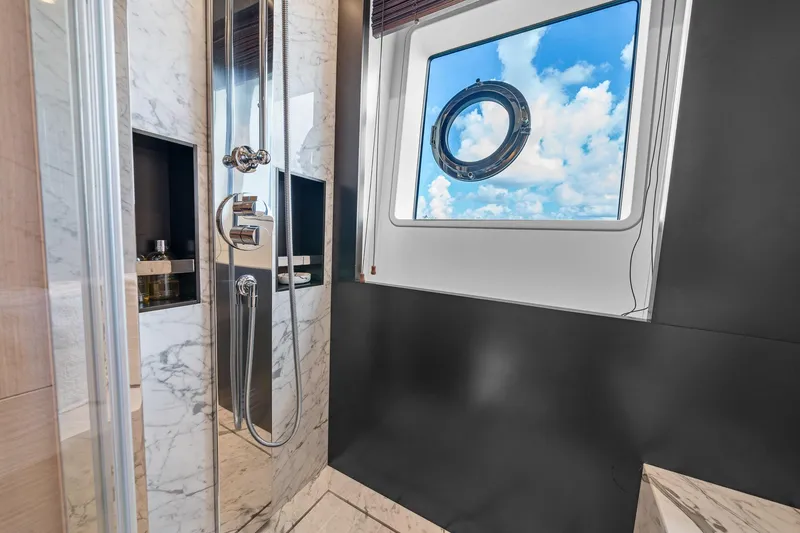 Slide: The Image of Luxurious bathroom with marble accents on Azimut Grande 27 METRI yacht, featuring a scenic porthole view. - 126