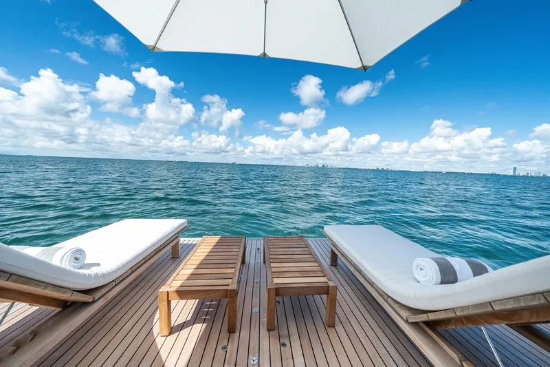 Slide: The Image of Luxurious Azimut Grande 27 METRI yacht deck with sun loungers, ocean view, and blue sky. - 50