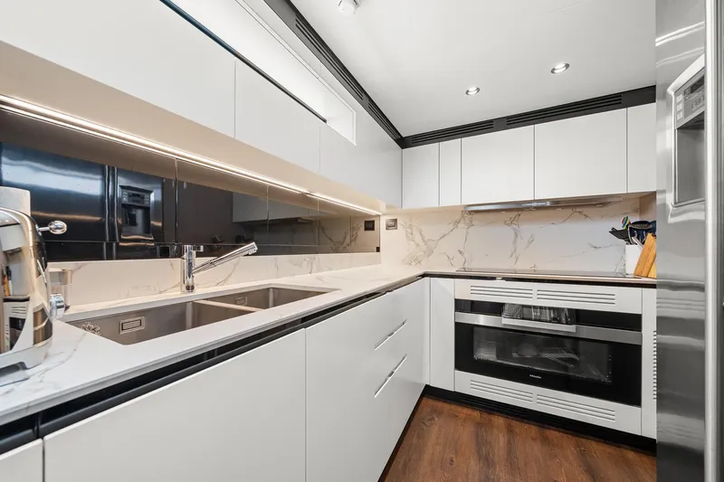 Slide: The Image of Modern kitchen interior on 2022 Azimut Grande 27 METRI yacht, featuring sleek white cabinetry and marble accents. - 70