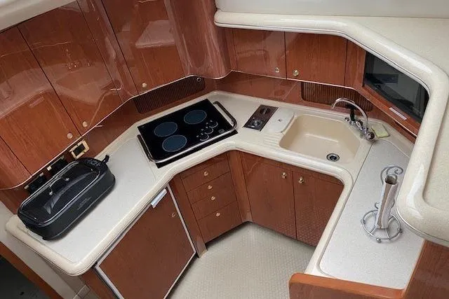 Slide: The Image of 1999 Sea Ray 420 Aft Cabin kitchen with stove, sink, and wooden cabinetry. - 13