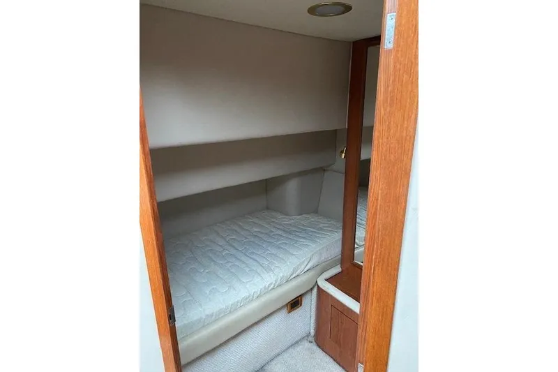 Slide: The Image of 1999 Sea Ray 420 Aft Cabin interior with cozy bed and wooden accents. - 14