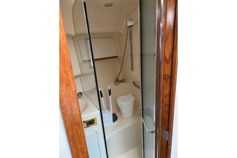 Slide: The Image of 1999 Sea Ray 420 Aft Cabin bathroom with shower, sink, and wooden door. - 16