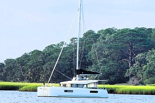 The Image of 2018 Lagoon 40 catamaran sailing near lush green shoreline. - 0