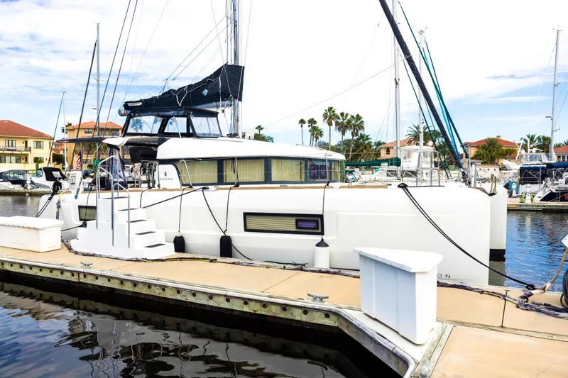 Slide: The Image of 2018 Lagoon 40 catamaran docked at a marina, surrounded by other boats and palm trees. - 3