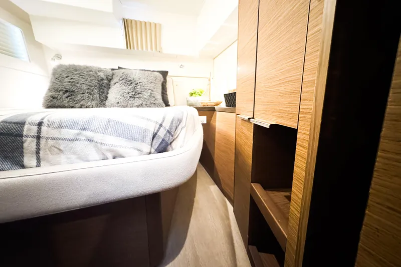 Slide: The Image of Cozy bedroom interior of 2018 Lagoon 40 catamaran with plush pillows and wooden cabinetry. - 44
