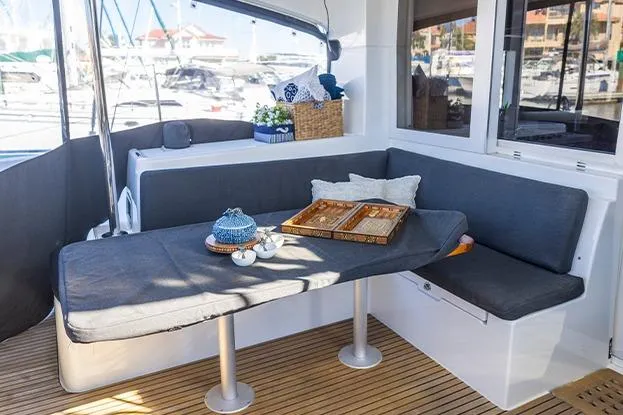 Slide: The Image of Cozy seating area on 2018 Lagoon 40 catamaran with table and cushions, docked at marina. - 65