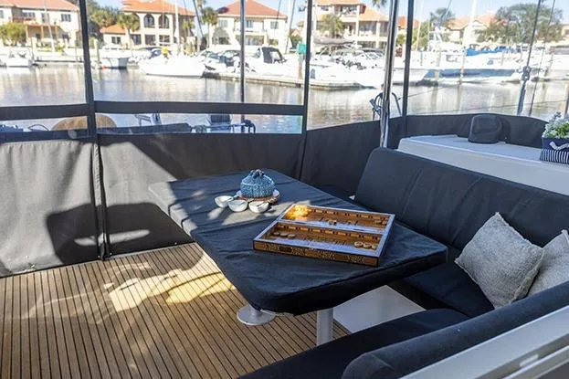 Slide: The Image of Cozy seating area on 2018 Lagoon 40 catamaran with game board and marina view. - 67