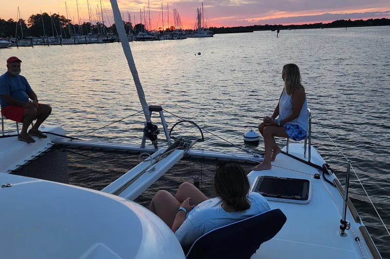 Slide: The Image of People relaxing on a 2018 Lagoon 40 catamaran at sunset, near a marina. - 8