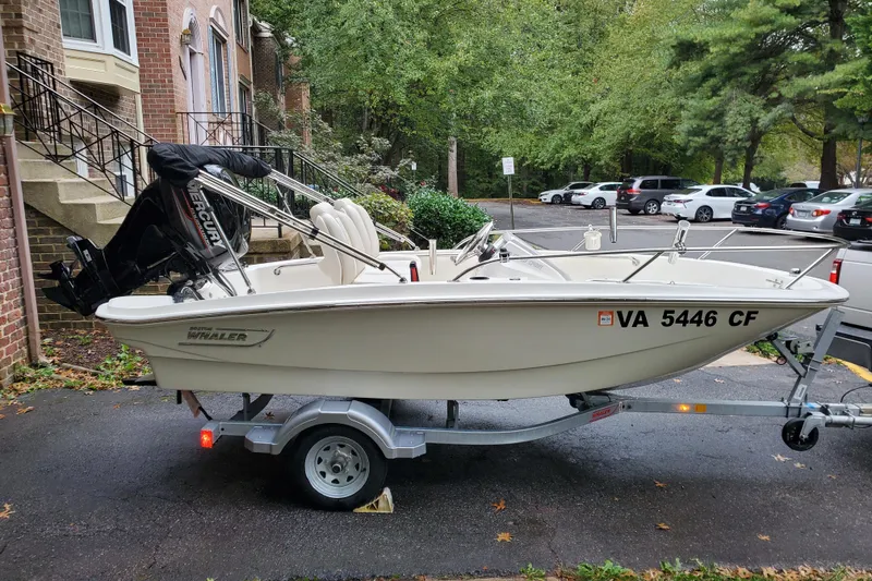 The Image of 2020 Boston Whaler 130 Super Sport boat on trailer, parked in residential area. - 0