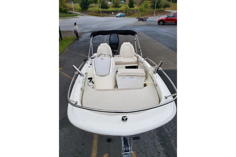 Slide: The Image of 2020 Boston Whaler 130 Super Sport boat with seating and steering wheel, parked on pavement. - 4