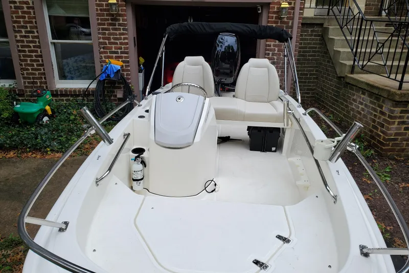 Slide: The Image of 2020 Boston Whaler 130 Super Sport boat parked in a driveway, showcasing interior seating and controls. - 8