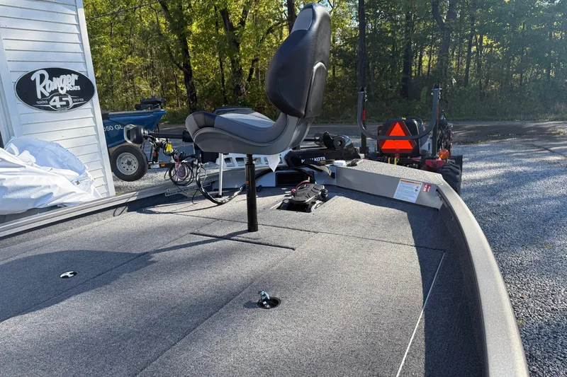 Slide: The Image of 2026 Crestliner XF189 boat deck with seat, parked outdoors near trees and equipment. - 7