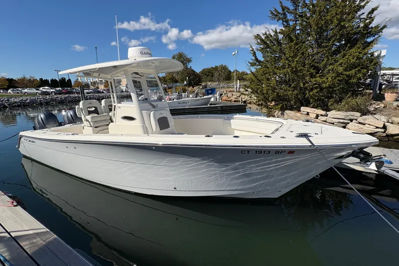 The Image of 2022 Cobia 280 Center Console boat docked in a marina under a clear blue sky. - 0