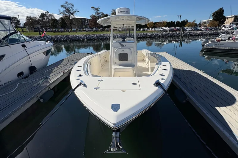 Slide: The Image of 2022 Cobia 280 Center Console boat docked in a marina under clear skies. - 1