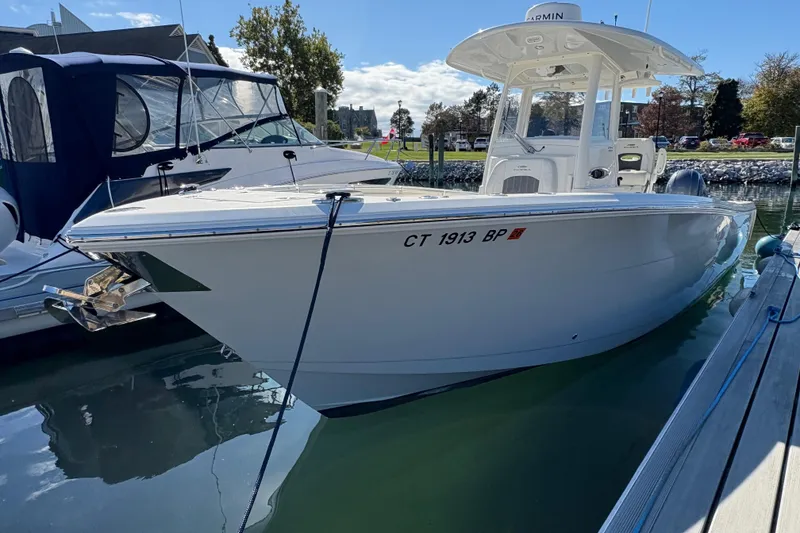 Slide: The Image of 2022 Cobia 280 Center Console boat docked in a marina under clear skies. - 2