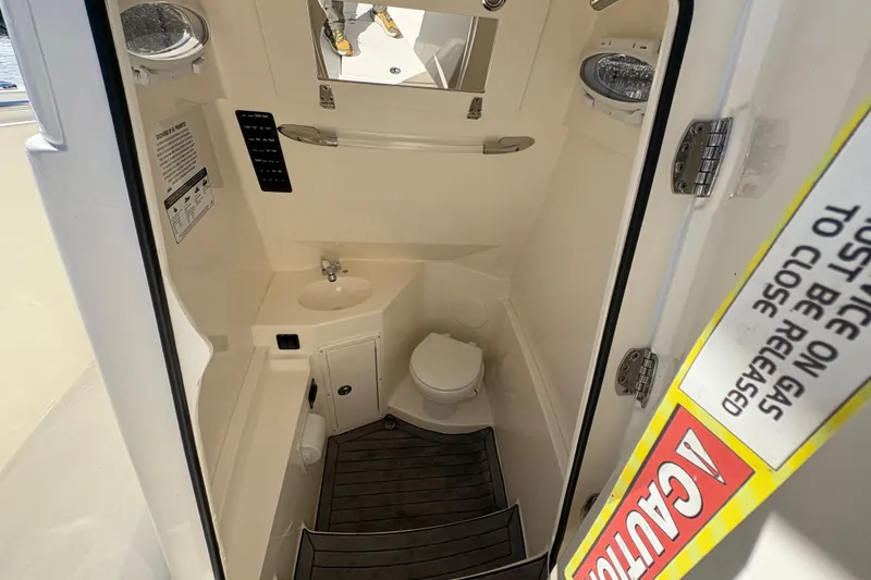 Slide: The Image of 2022 Cobia 280 Center Console boat interior with compact bathroom and sink. - 26