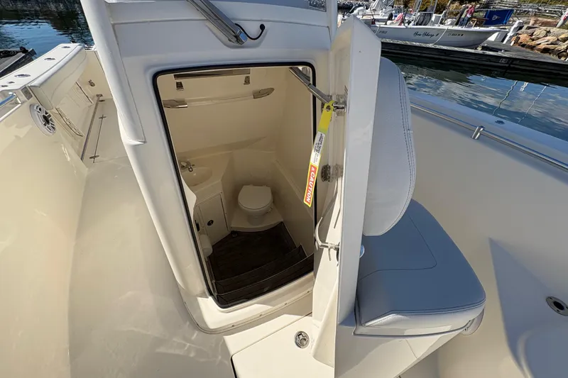 Slide: The Image of 2022 Cobia 280 Center Console boat with open cabin door revealing interior amenities. - 27
