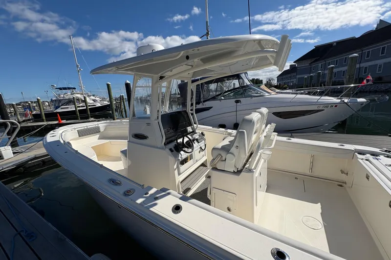 Slide: The Image of 2022 Cobia 280 Center Console boat docked at marina under clear blue sky. - 30