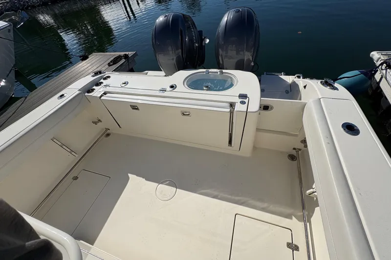 Slide: The Image of 2022 Cobia 280 Center Console boat deck with twin engines, docked at marina. - 40