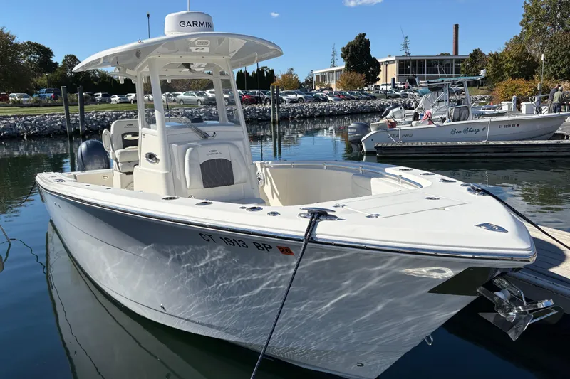 Slide: The Image of 2022 Cobia 280 Center Console boat docked in a marina under clear blue skies. - 45