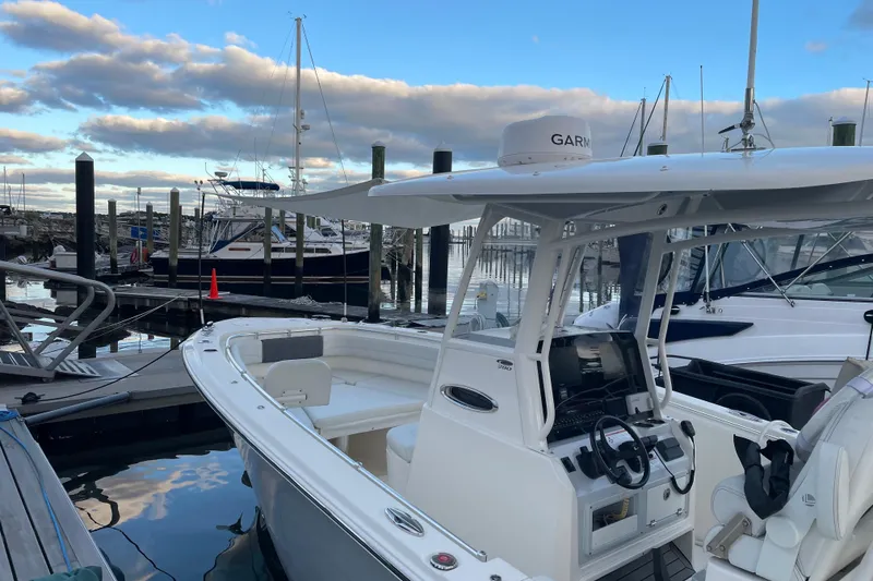 Slide: The Image of 2022 Cobia 280 Center Console boat docked at marina under cloudy sky. - 58