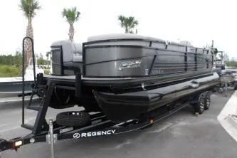 The Image of 2021 Regency 250 LE3 Sport pontoon boat on trailer, parked outdoors. - 0