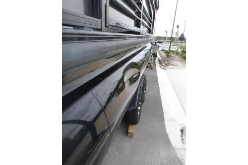 Slide: The Image of 2021 Regency 250 LE3 Sport boat, sleek black exterior, parked on a street. - 9