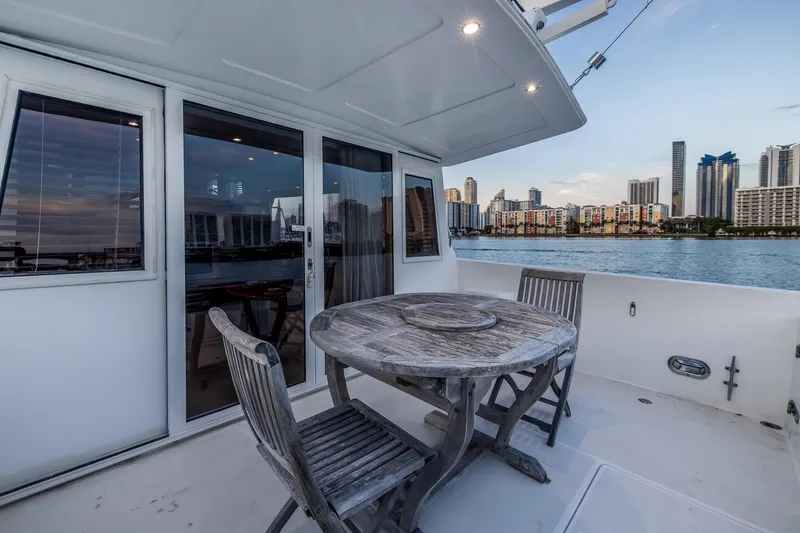Slide: The Image of 2003 Navigator Rival 5700 yacht deck with wooden table, chairs, and city skyline view. - 16