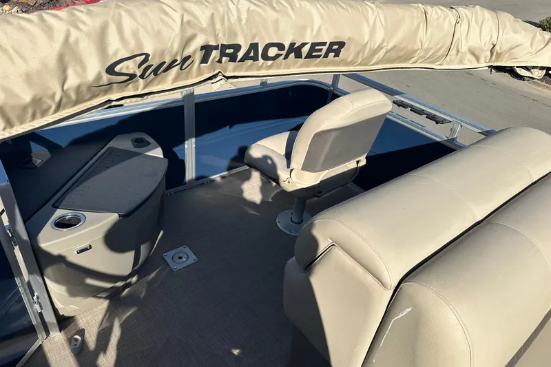 Slide: The Image of 2025 Sun Tracker Fishin' Barge 20 DLX interior with beige seating and console. - 8