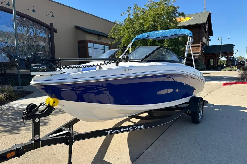 Slide: The Image of 2024 Tahoe 185 S boat on trailer, blue and white design, parked outdoors. - 1