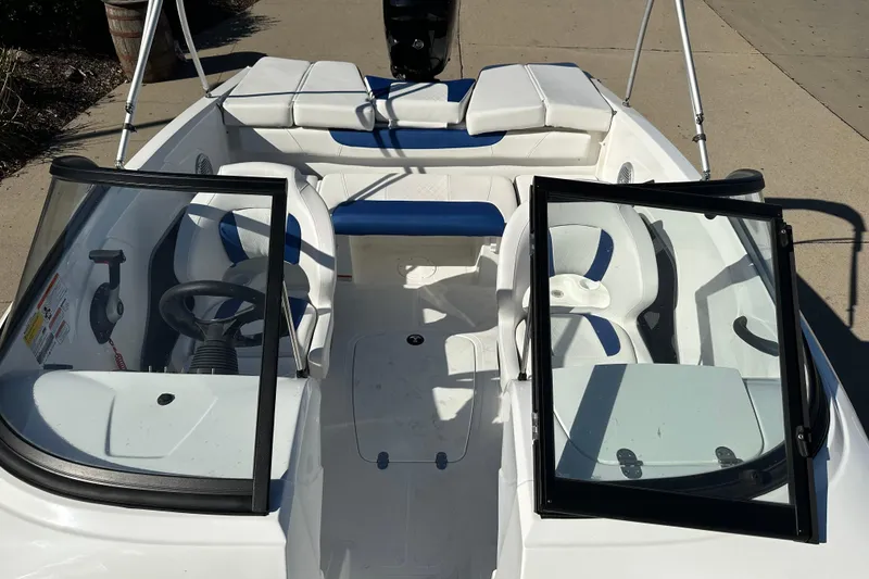 Slide: The Image of 2024 Tahoe 185 S boat interior with seating and steering wheel, docked on concrete. - 9