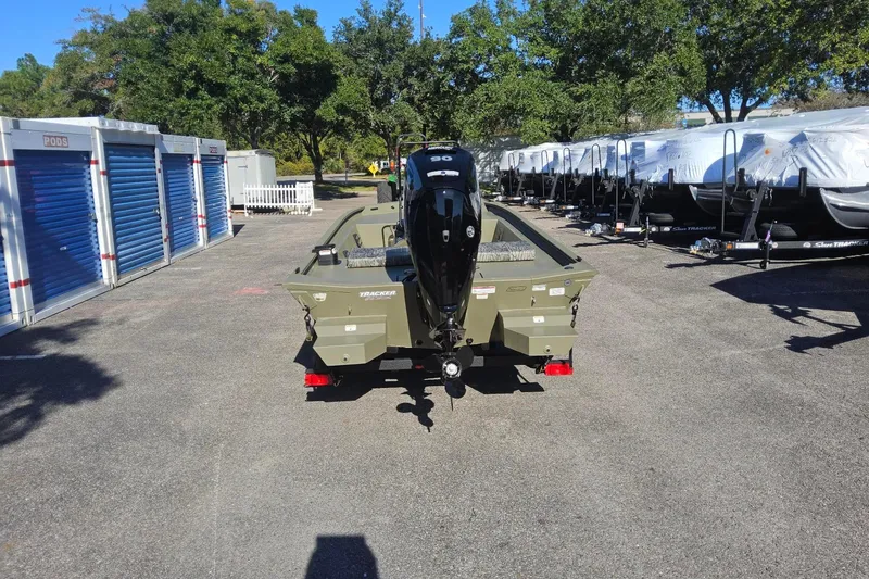 Slide: The Image of 2026 Tracker Grizzly 1860 CC boat with motor, parked outdoors near storage units. - 3