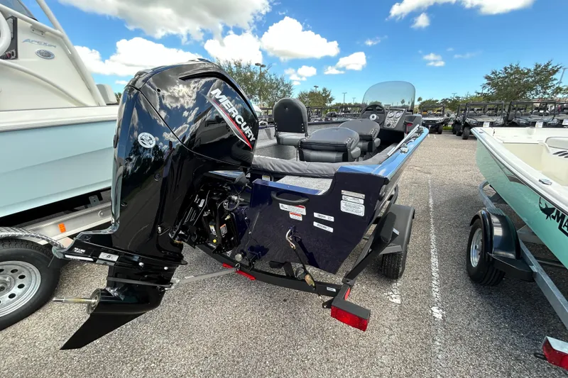Slide: The Image of 2026 Tracker Pro Guide V-16 SC boat with Mercury outboard motor in parking lot. - 2