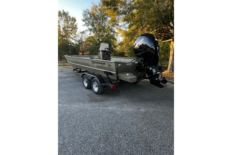 Slide: The Image of 2026 Tracker Grizzly 2072 CC boat on trailer, parked outdoors, surrounded by trees. - 2