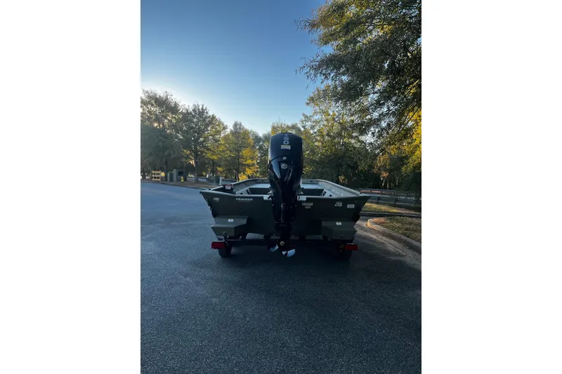 Slide: The Image of 2026 Tracker Grizzly 2072 CC boat on trailer, parked on a tree-lined street. - 3