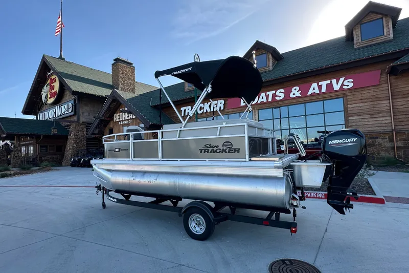 The Image of 2026 Sun Tracker Bass Buggy 16 XL Select pontoon boat outside a store with Mercury engine. - 4