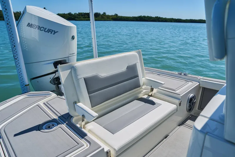 Slide: The Image of Man organizing fishing rods on a 2026 Mako 24 APEX boat in clear blue waters. - 68