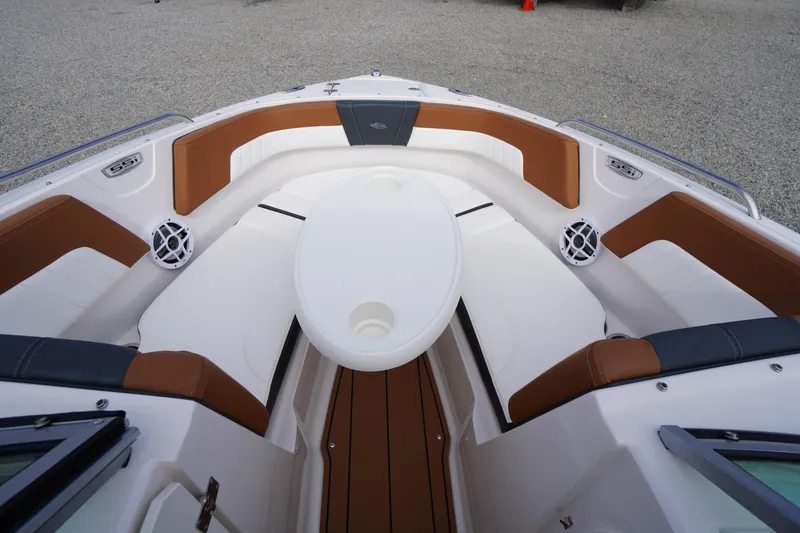 Slide: The Image of 2023 Chaparral 23 SSi OB boat interior with brown and white seating, round table, and speakers. - 13