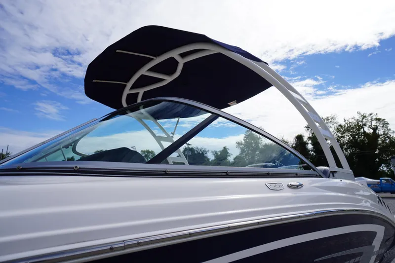 Slide: The Image of 2023 Chaparral 23 SSi OB boat with sleek design and canopy under blue sky. - 2