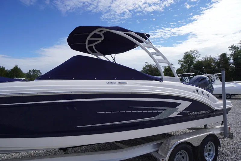 Slide: The Image of 2023 Chaparral 23 SSi OB boat with sleek design on a trailer under blue sky. - 3