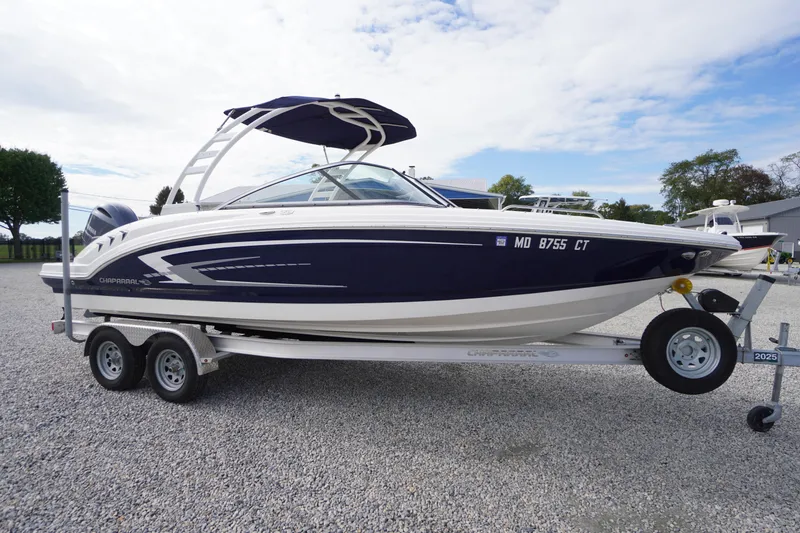 Slide: The Image of 2023 Chaparral 23 SSi OB boat on trailer, blue and white design, parked outdoors. - 59
