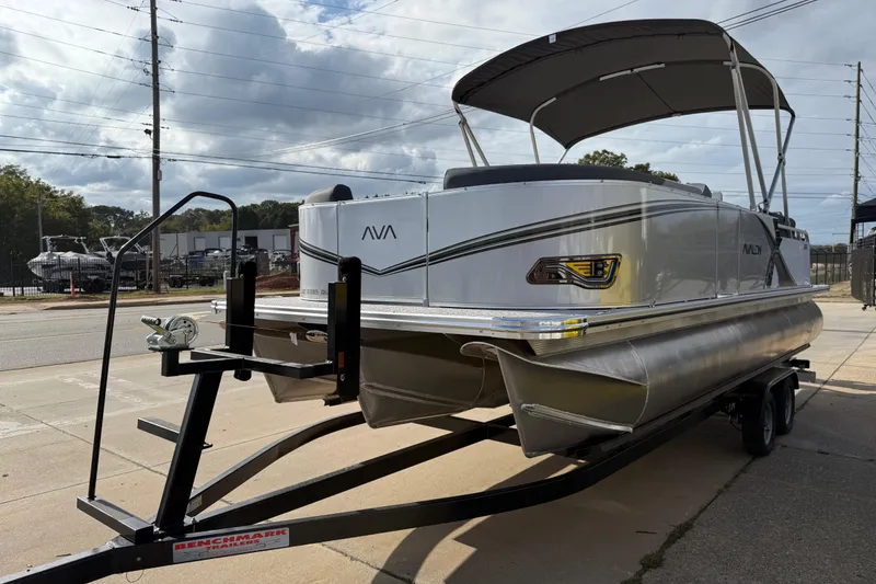 Slide: The Image of 2026 Avalon LSZ Quad Lounger Shift pontoon boat on trailer, parked outdoors. - 2